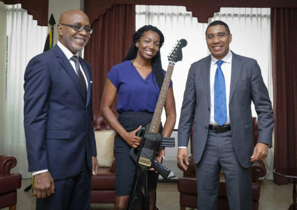 Jamaican Prime Minister Andrew Holness (Right) with Niambe McIntosh (Center, holding her Father’s M16 guitar) and Chairman of Pulse Kingsley Cooper (Left) at Jamaica House